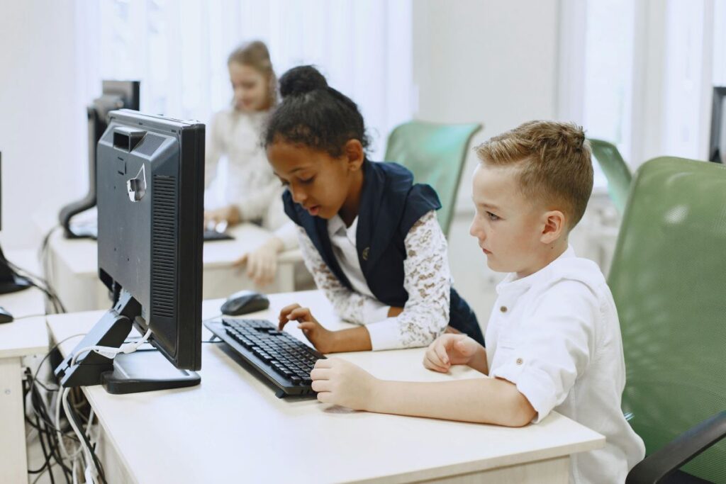 Young students working on a desktop computer in a classroom